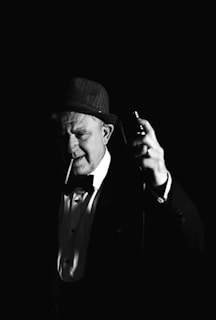 A shadowy figure in a fedora leans over a vintage microphone, bathed in moody, cinematic lighting.
