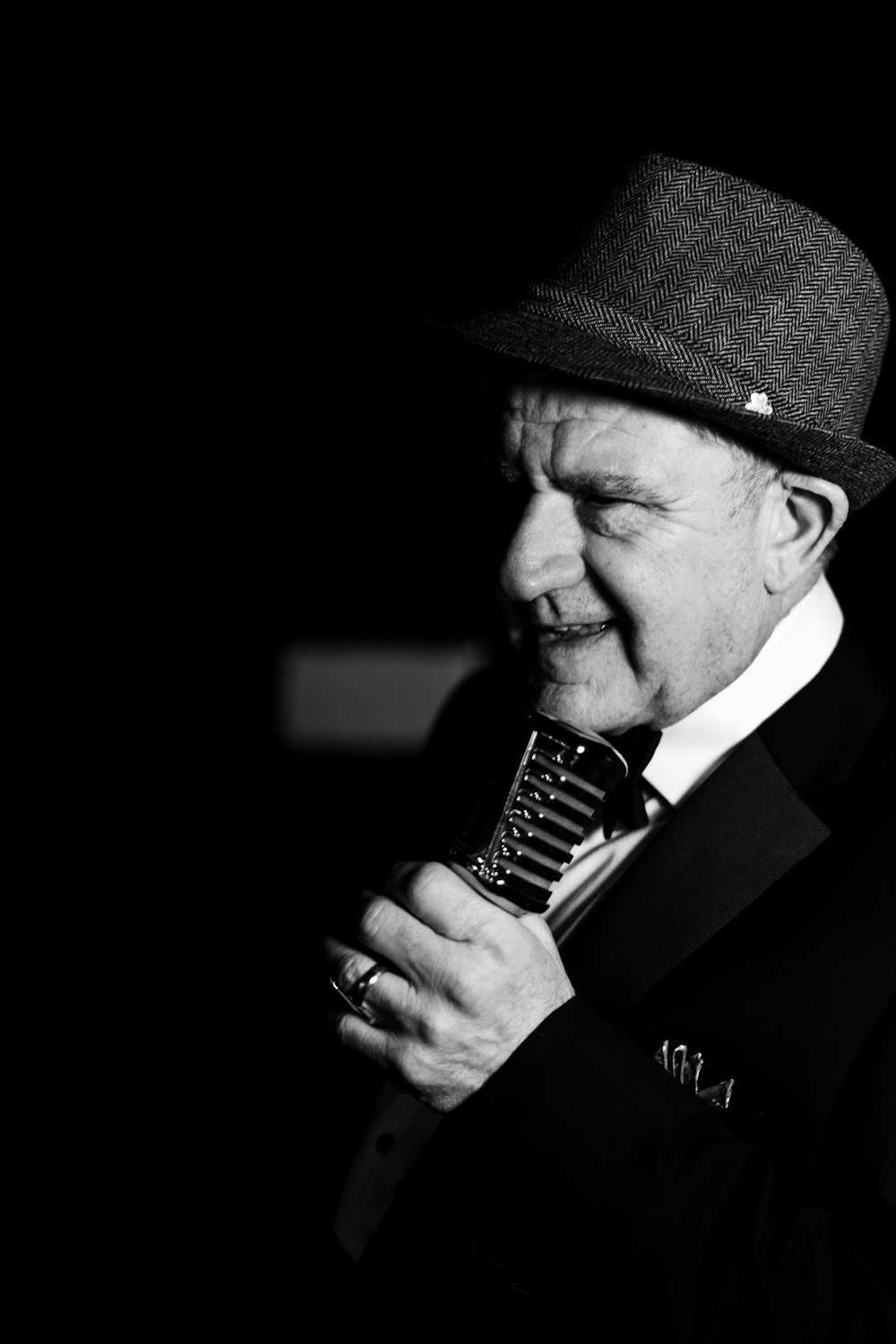 a man in a suit and hat holding a microphone