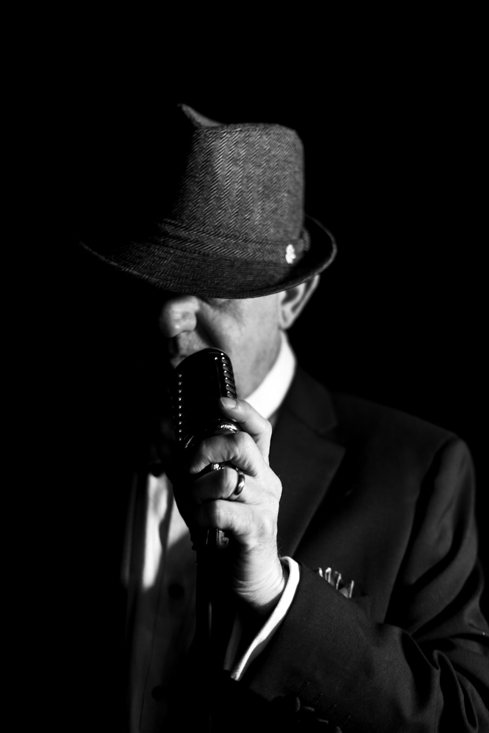 a man in a suit and hat holding a cell phone