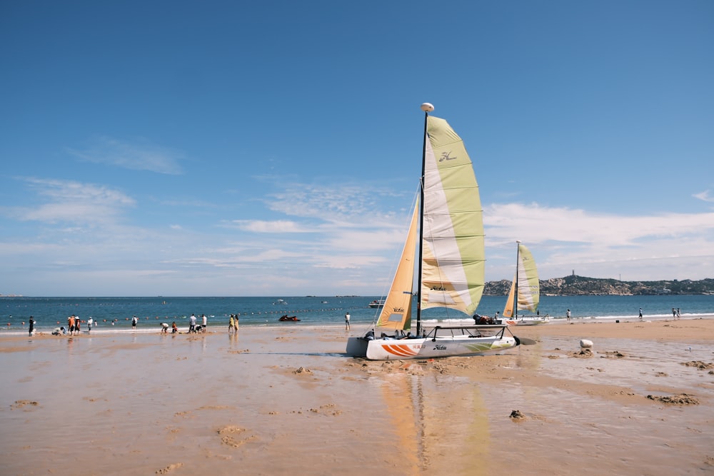 a sailboat on a beach with people in the background