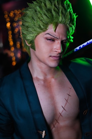 A person with green hair styled upwards and exaggerated facial features stands confidently, wearing a dark robe-like outfit with a visible scar across the chest. They hold a katana with a distinctive blue pattern.