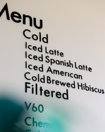 A partial view of a cafe menu displaying various cold and filtered beverage options, including types of lattes, cold brews, and filtering methods.