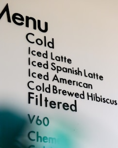 A partial view of a cafe menu displaying various cold and filtered beverage options, including types of lattes, cold brews, and filtering methods.