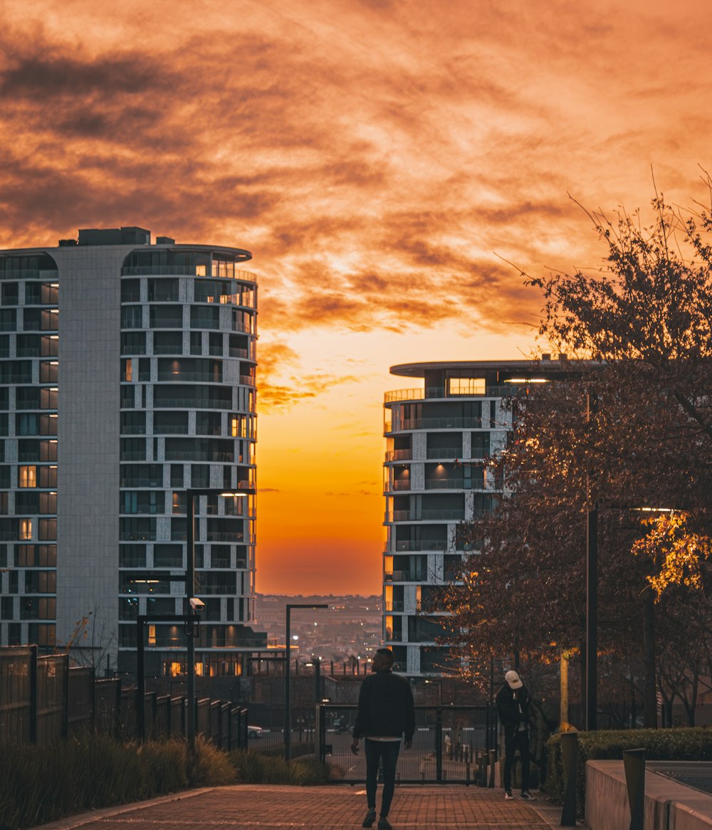 a man walking down a sidewalk next to tall buildings