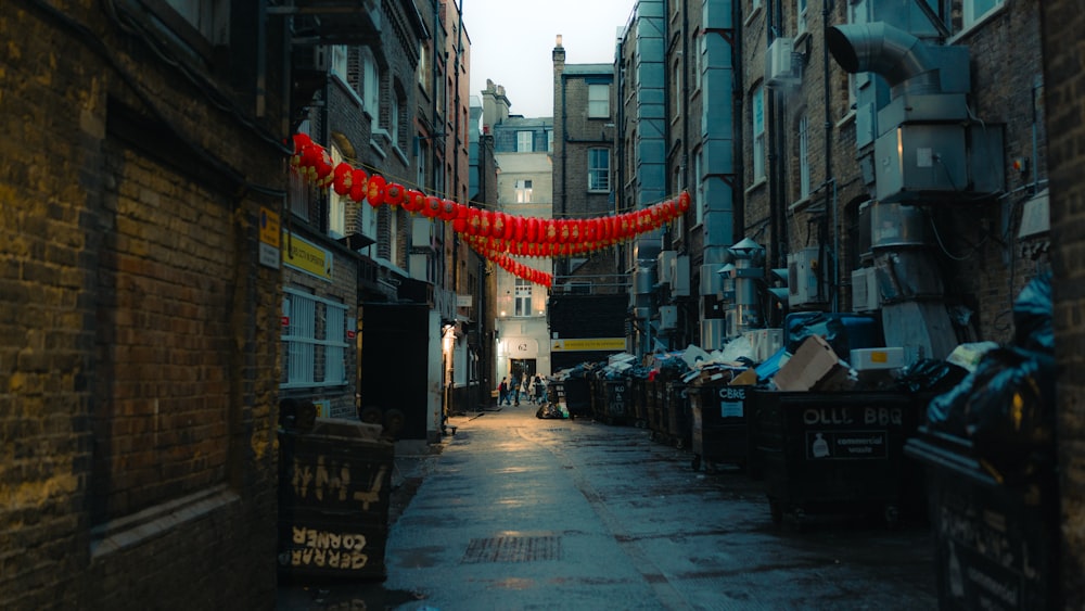 a narrow city street with a red ribbon hanging from the buildings