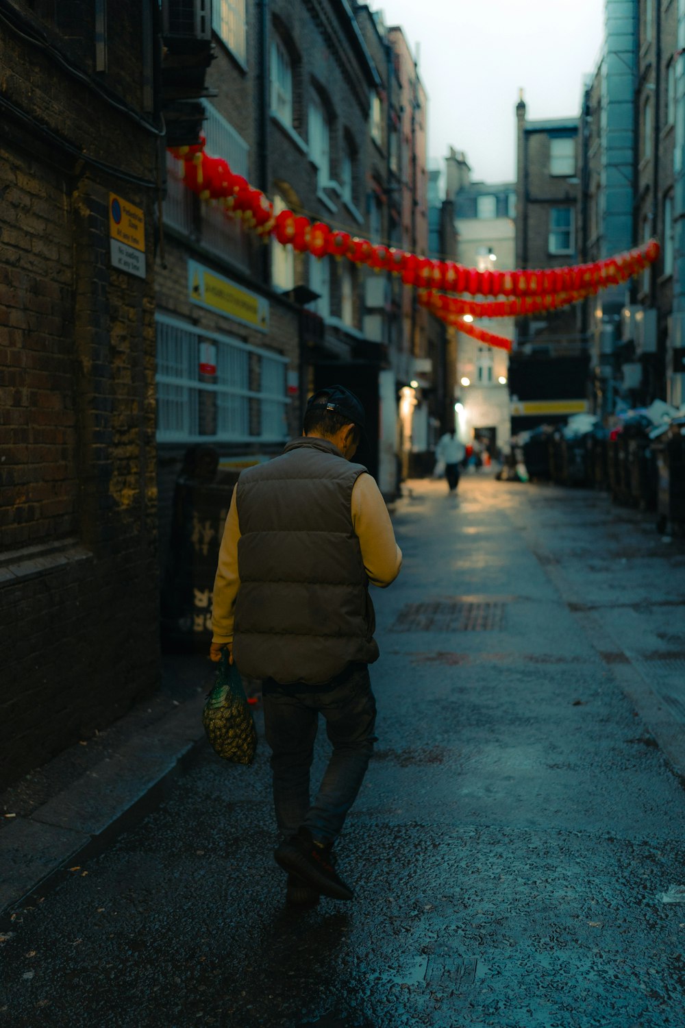 a man walking down a street next to tall buildings