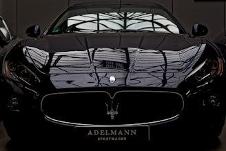 A sleek black sports car gleaming under soft lighting, showcasing a flawless, mirror-like finish.