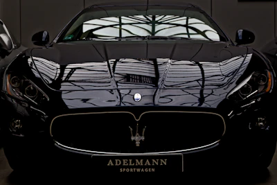 Sleek black sports car gleaming under soft lighting after an expert exterior detail.