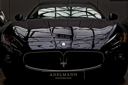 A sleek black sports car gleaming under soft neon highlights after detailing.