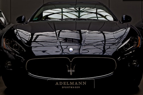 A sleek black sports car parked under soft lighting highlighting its curves.