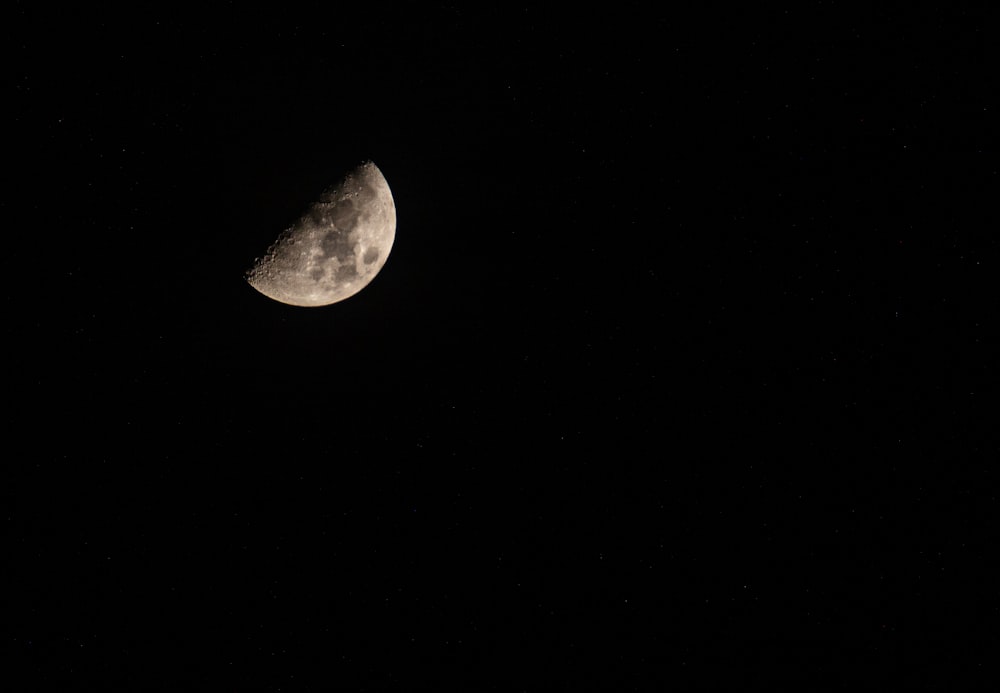 a half moon is seen in the dark sky