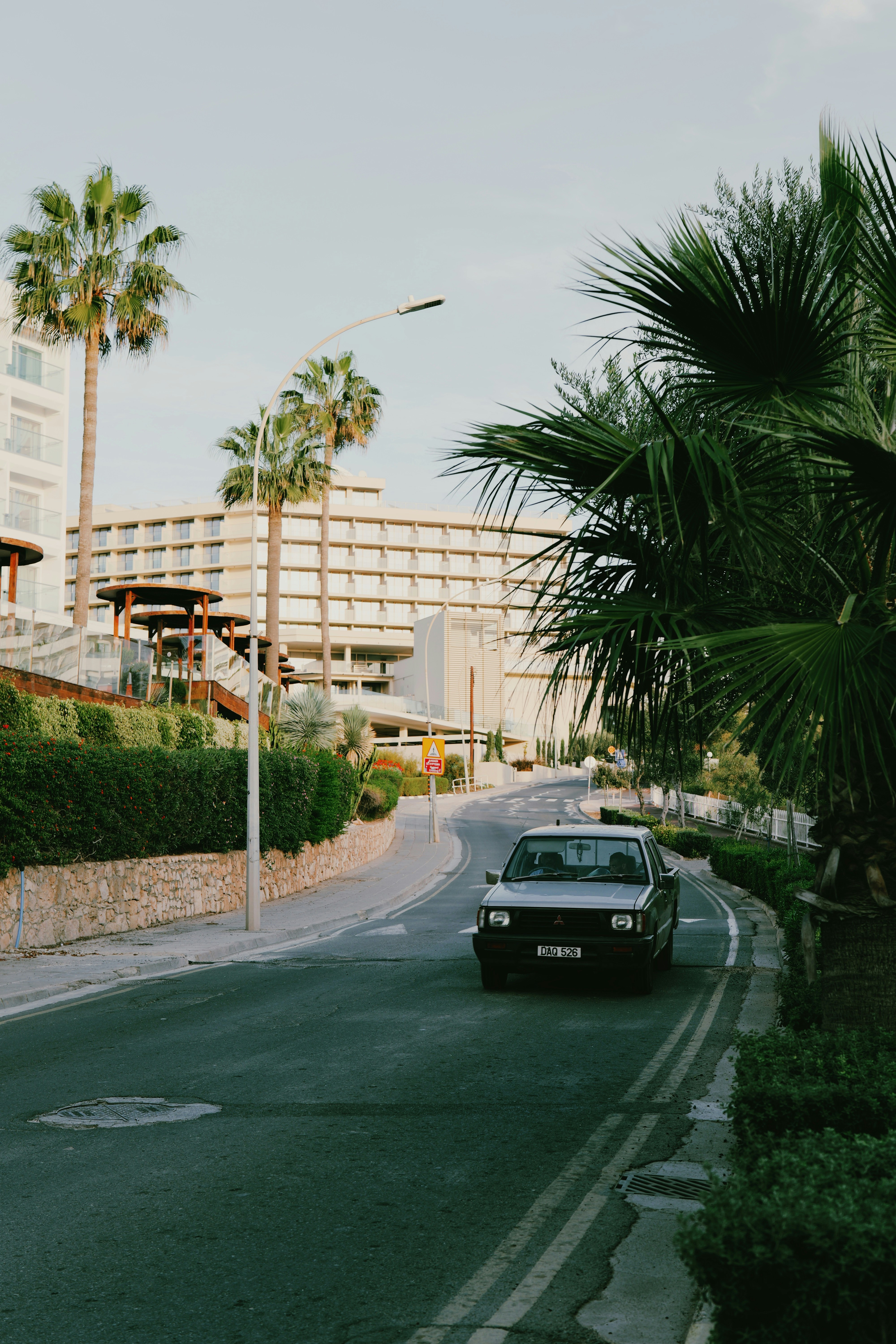 a car driving down a street next to palm trees