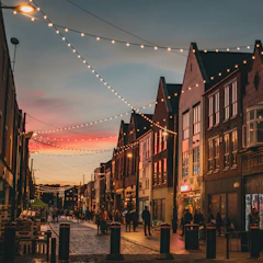 A charming baroque village street with ornate architecture and warm glowing lanterns at dusk.