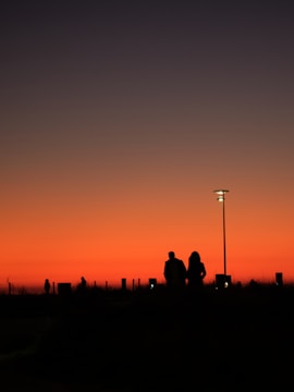 A mentor and a boy walking together along a soft purple-hued trail at sunset.