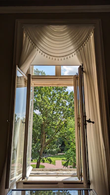 Serene garden view from a Senai homestay window, framed by soft curtains.