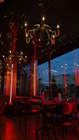 A luxurious restaurant interior illuminated by deep crimson-hued chandeliers creating an intimate atmosphere.