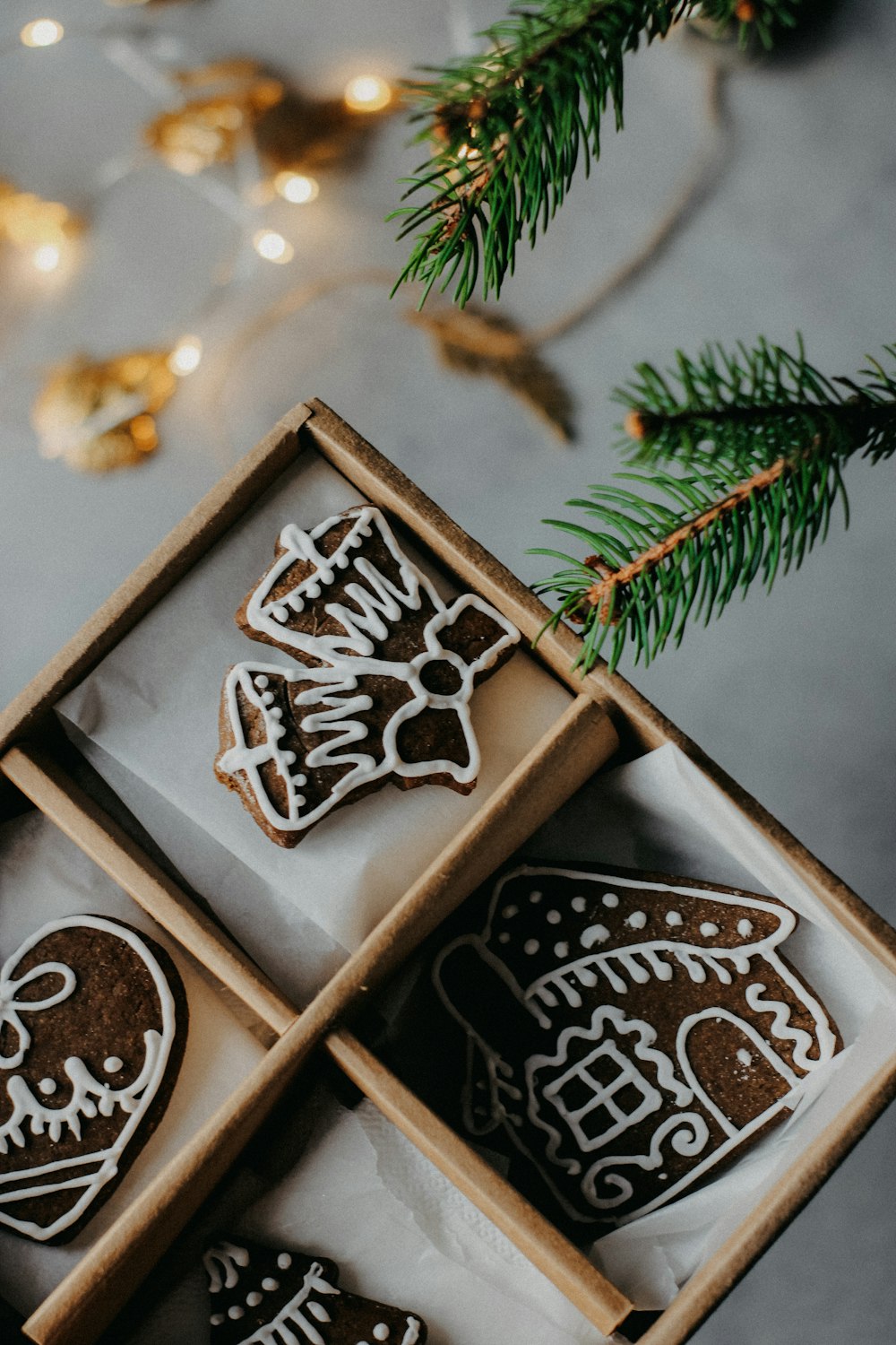 three decorated cookies in a box next to a christmas tree