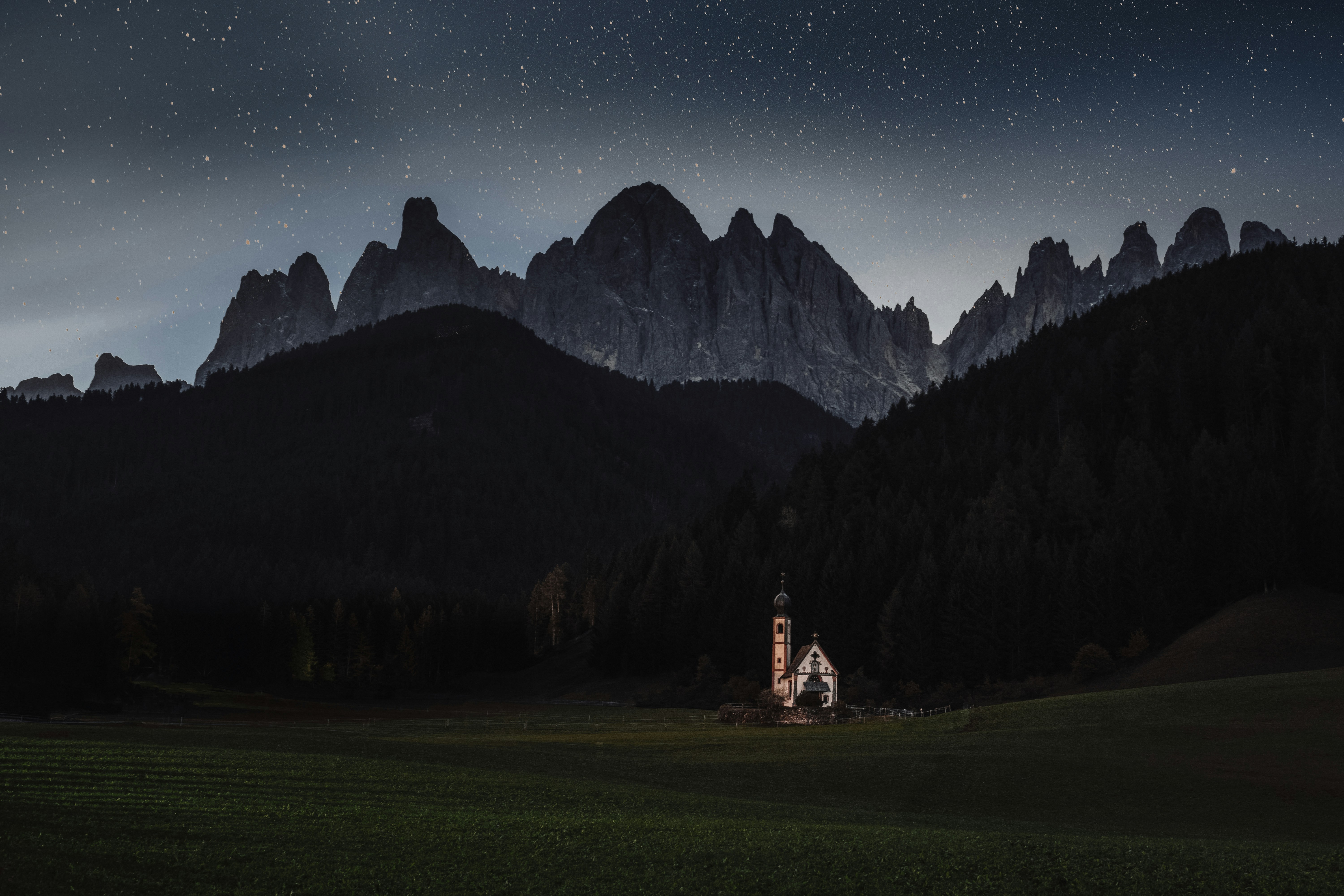 Una chiesa in mezzo a un campo con le montagne sullo sfondo foto ...