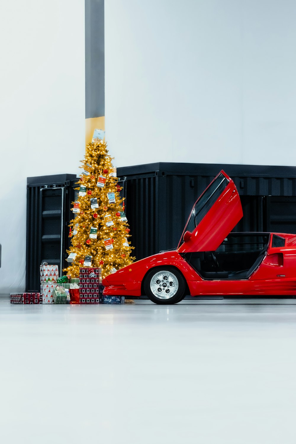 a red sports car parked next to a christmas tree