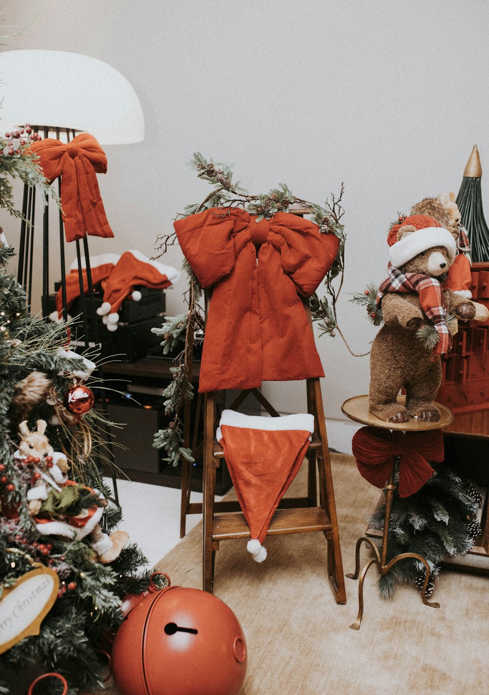 a teddy bear sitting on a stool next to a christmas tree