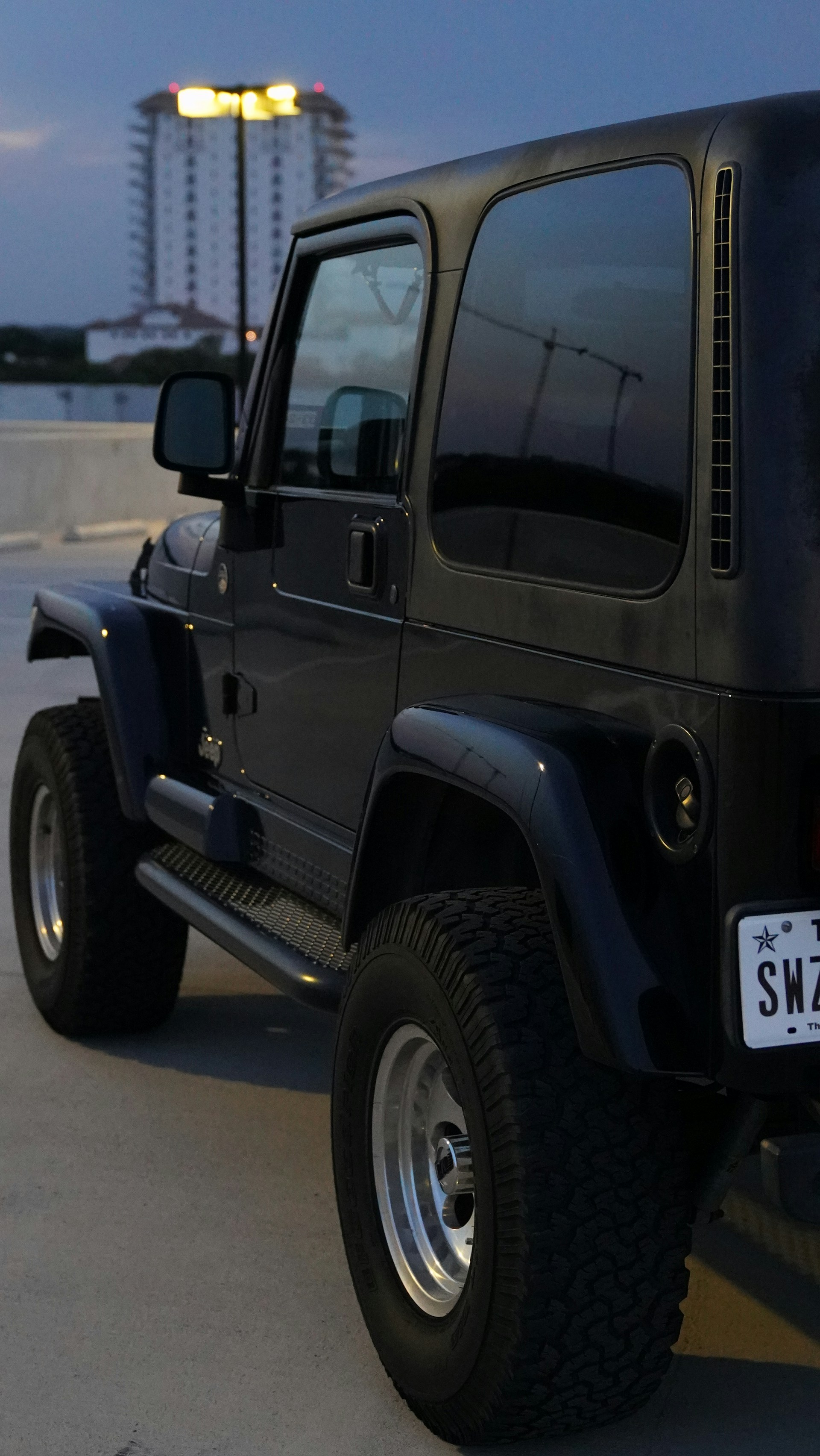 Night shot of a Jeep Merapi parked on a mountain ridge with neon-lit UI elements highlighting the vehicle's features.