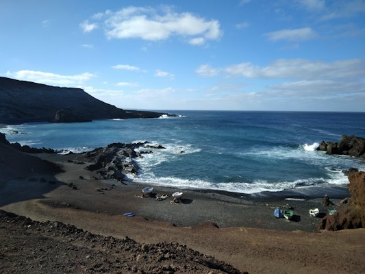 People on a dark volcanic beach — Lanzarote, Spain