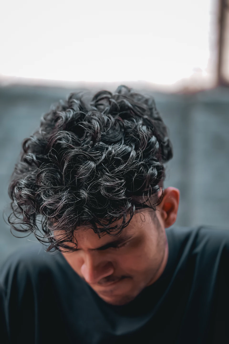 Homme aux cheveux courts bouclés, tête baissée