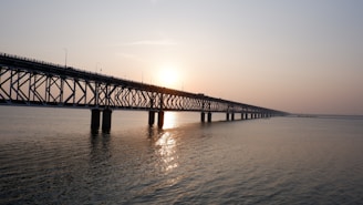 Engineer inspecting a complex bridge structure with advanced tools during sunset.