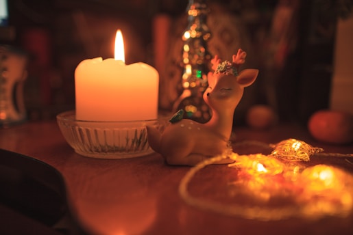 a lit candle and a deer figurine on a table