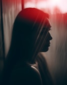 A silhouette of a model framed by soft, reddish light in a shadowy setting.