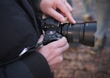 A photographer adjusting settings on a camera in nature.