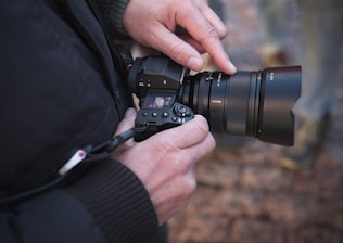 A photographer adjusting settings on a professional camera in a natural landscape.
