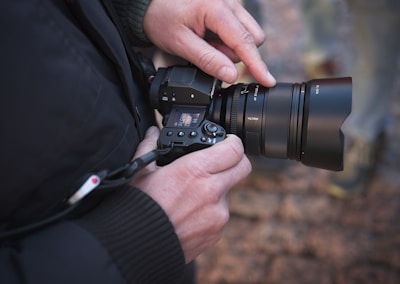 A photographer adjusting settings on a camera in nature.