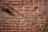 Red bricks are arranged in a tightly knit pattern, showing both the texture and mortar lines clearly. The surface is well-lit, emphasizing the rough texture and natural color variations found in the bricks. Some shadows are cast across the bricks, adding depth to the flat surface.