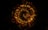 A swirling pattern of glowing, bokeh-like light particles in hues of gold and red against a dark background creates a mesmerizing and dynamic visual effect.