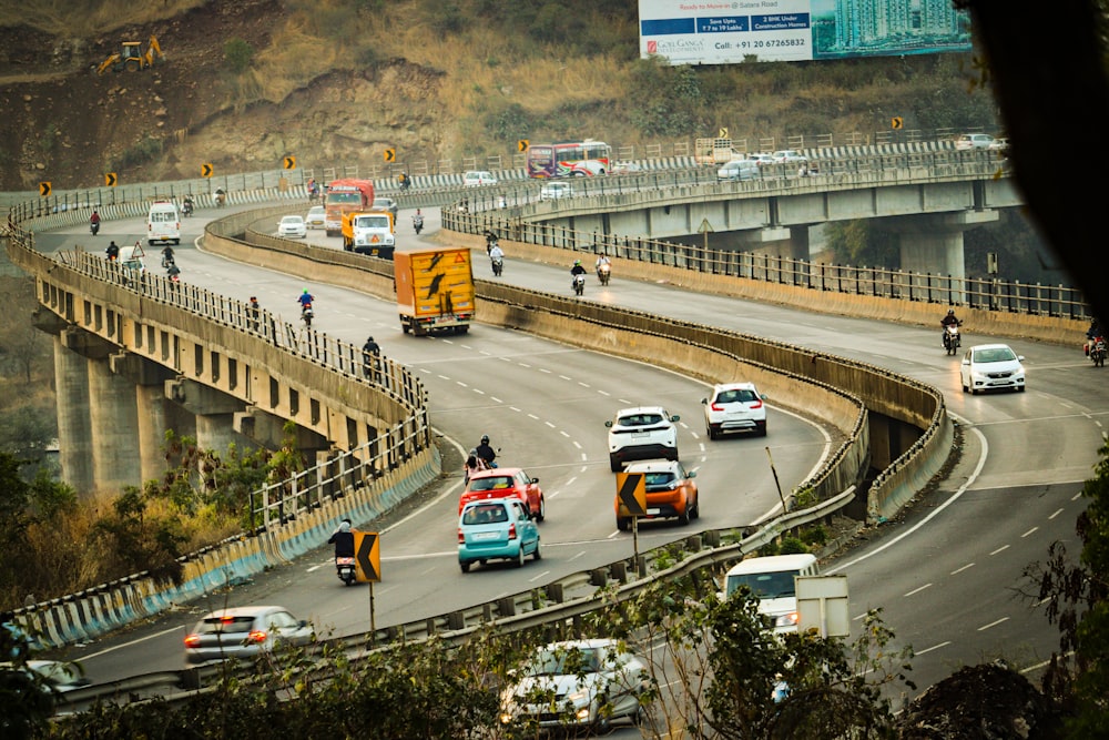 a group of cars driving down a highway next to a bridge