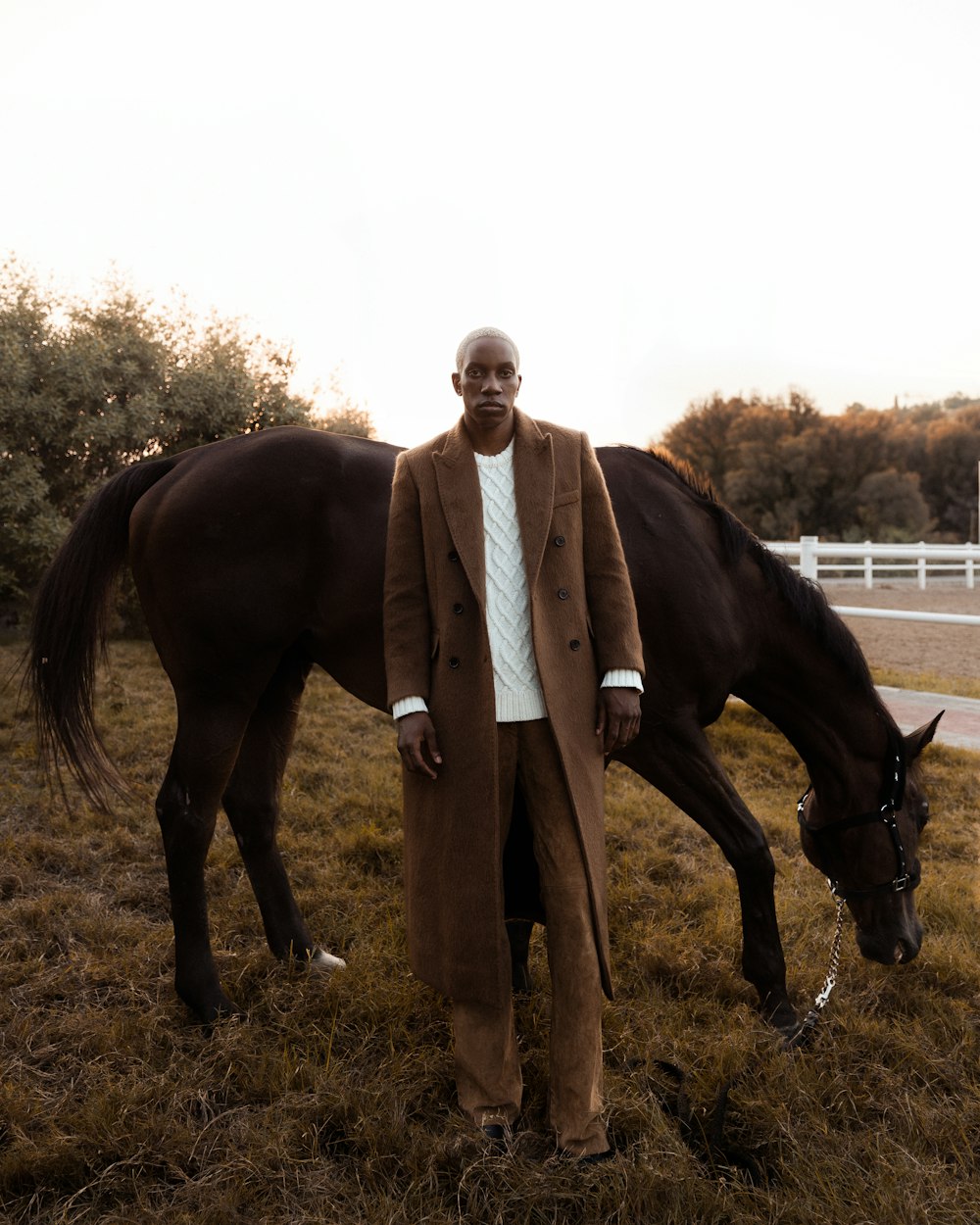 a man standing next to a horse in a field