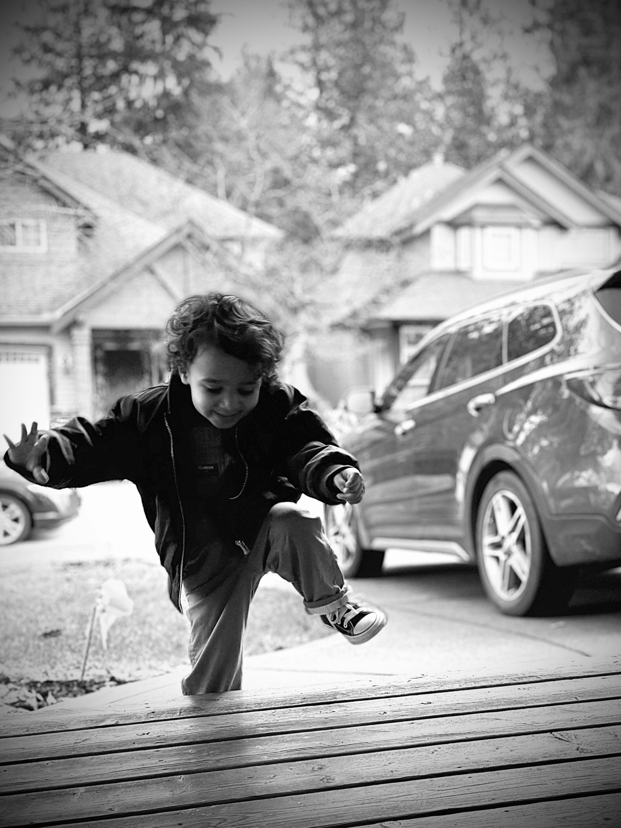 a young boy jumping in the air on a wooden deck