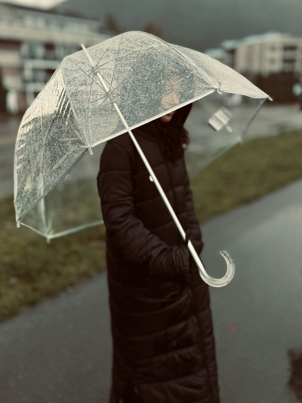 a woman in a black coat holding a clear umbrella