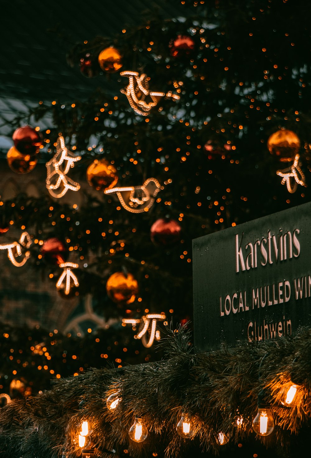 a christmas tree with lights and a sign in front of it