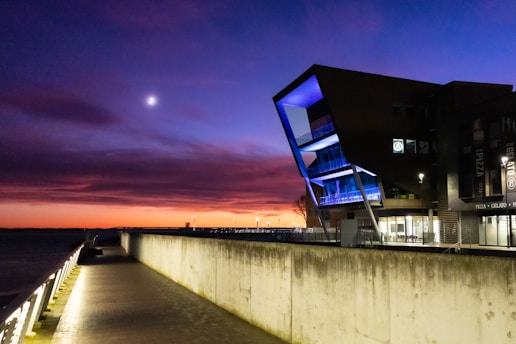 A modern hospital building with glowing teal and blue accents during sunrise.