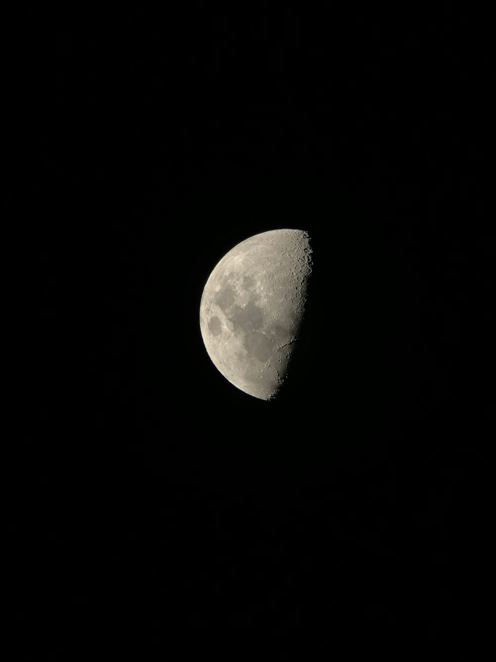 a half moon is seen in the dark sky