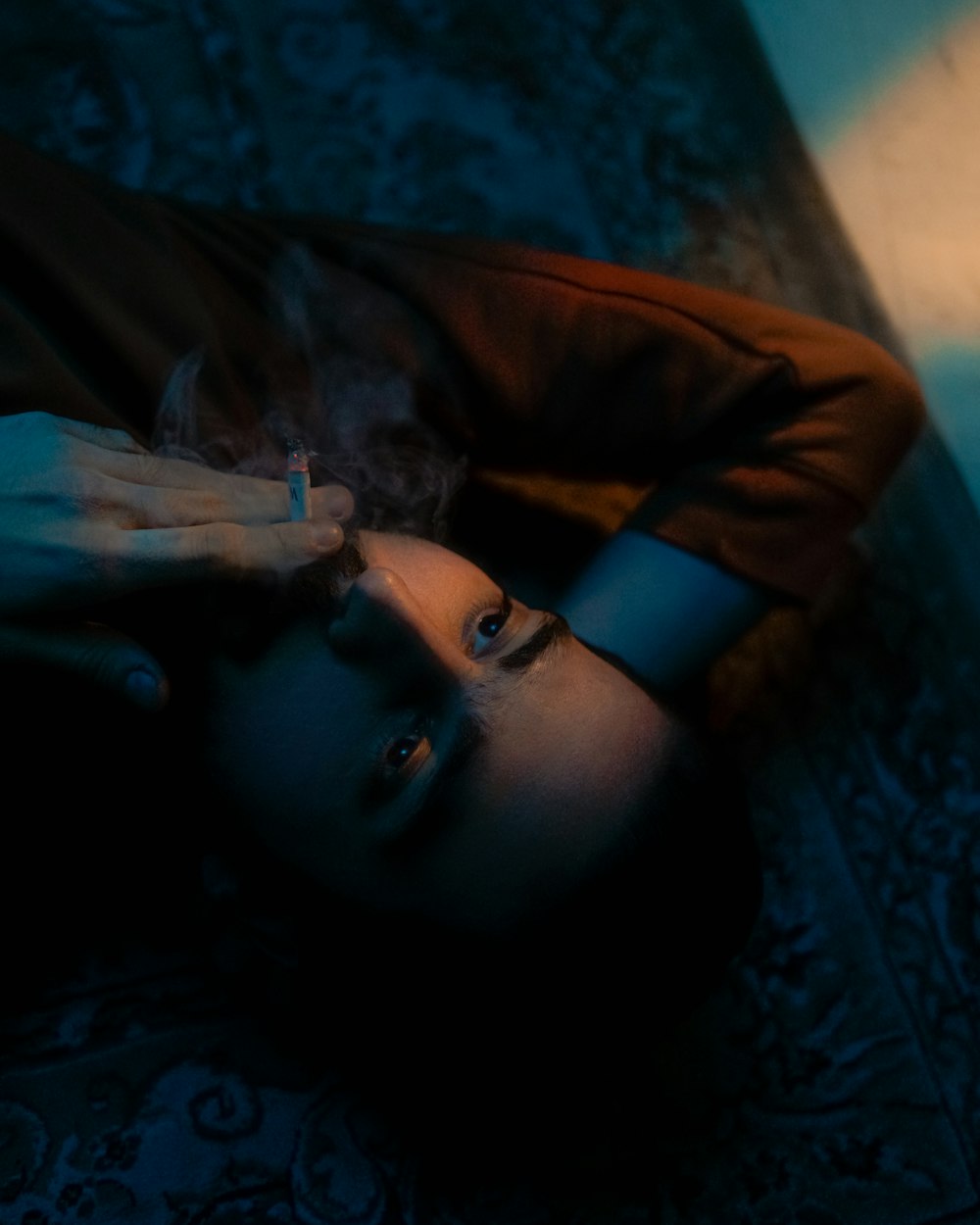 a person laying on the floor with a cigarette in their mouth
