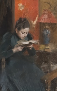 A woman in a dark dress is deeply focused while reading a book. She is seated in a dimly lit room adorned with an ornate red wallpaper featuring floral patterns. In the background, a small table holds a decorative lamp with a red shade and a blue vase.