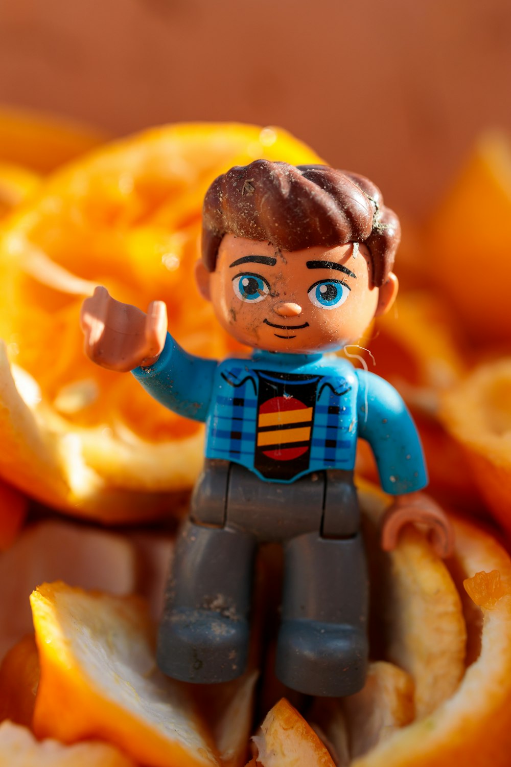 a toy figurine sitting on top of a pile of sliced oranges