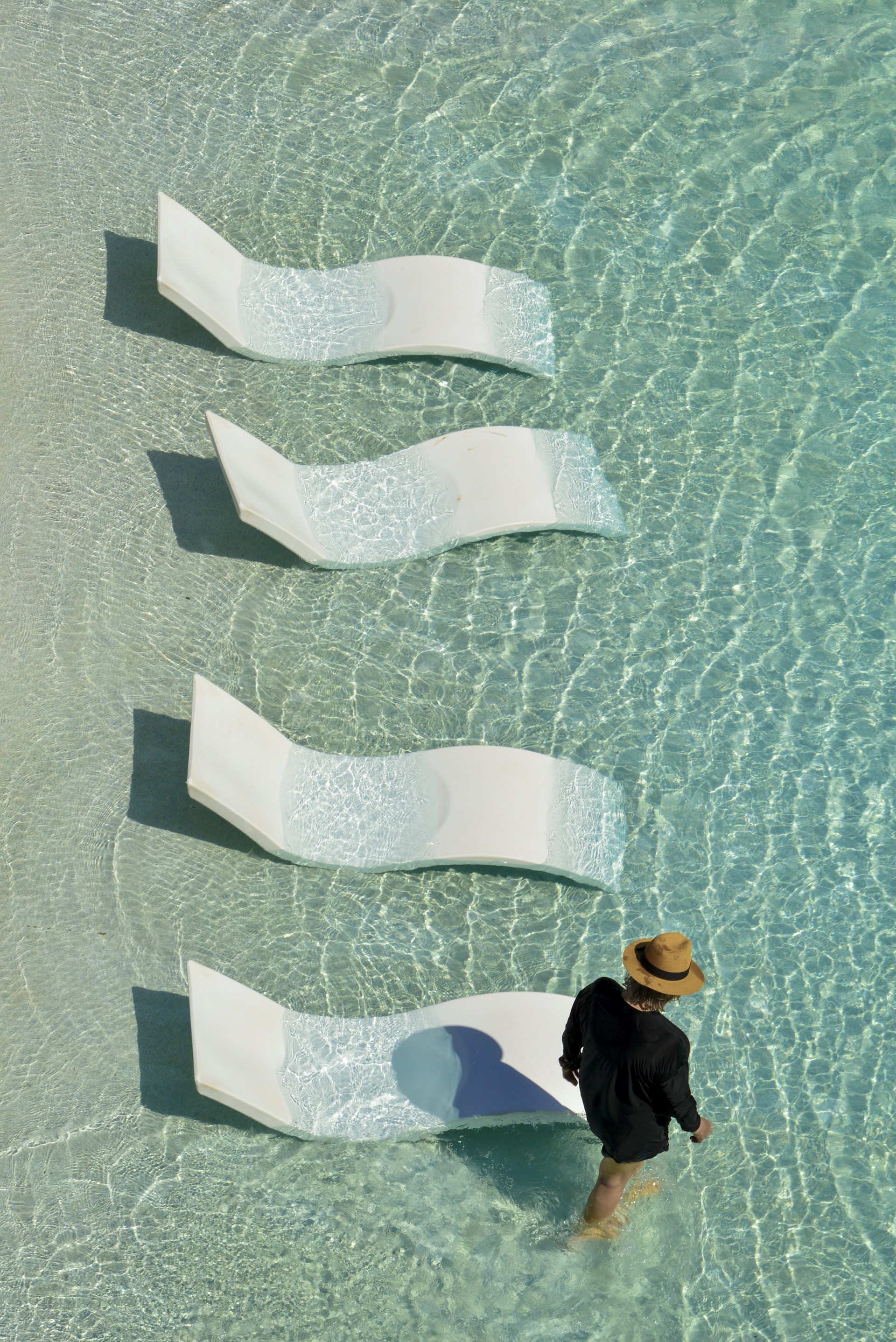 a man standing in the water next to a row of white chairs