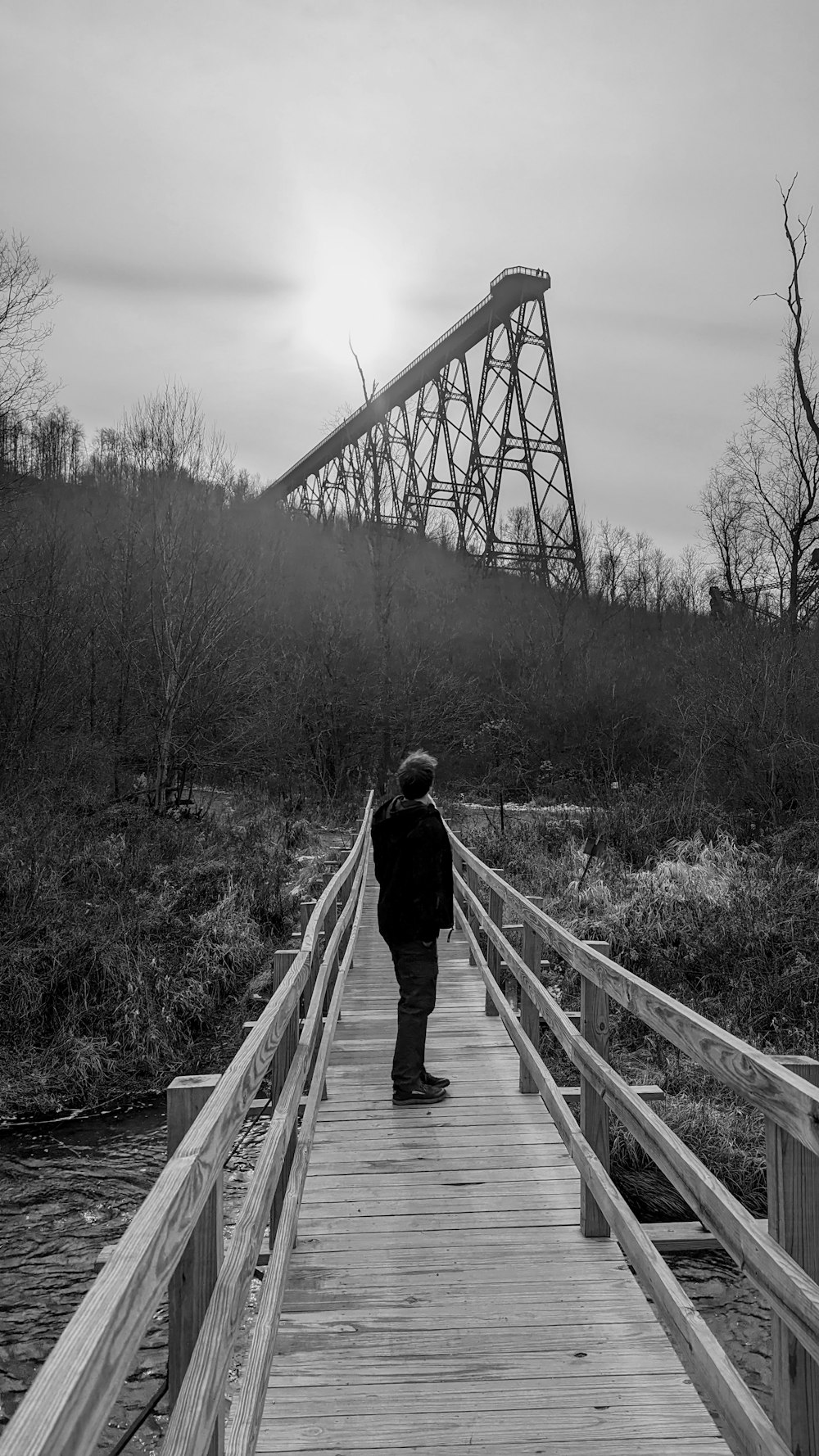 a person walking across a wooden bridge over water