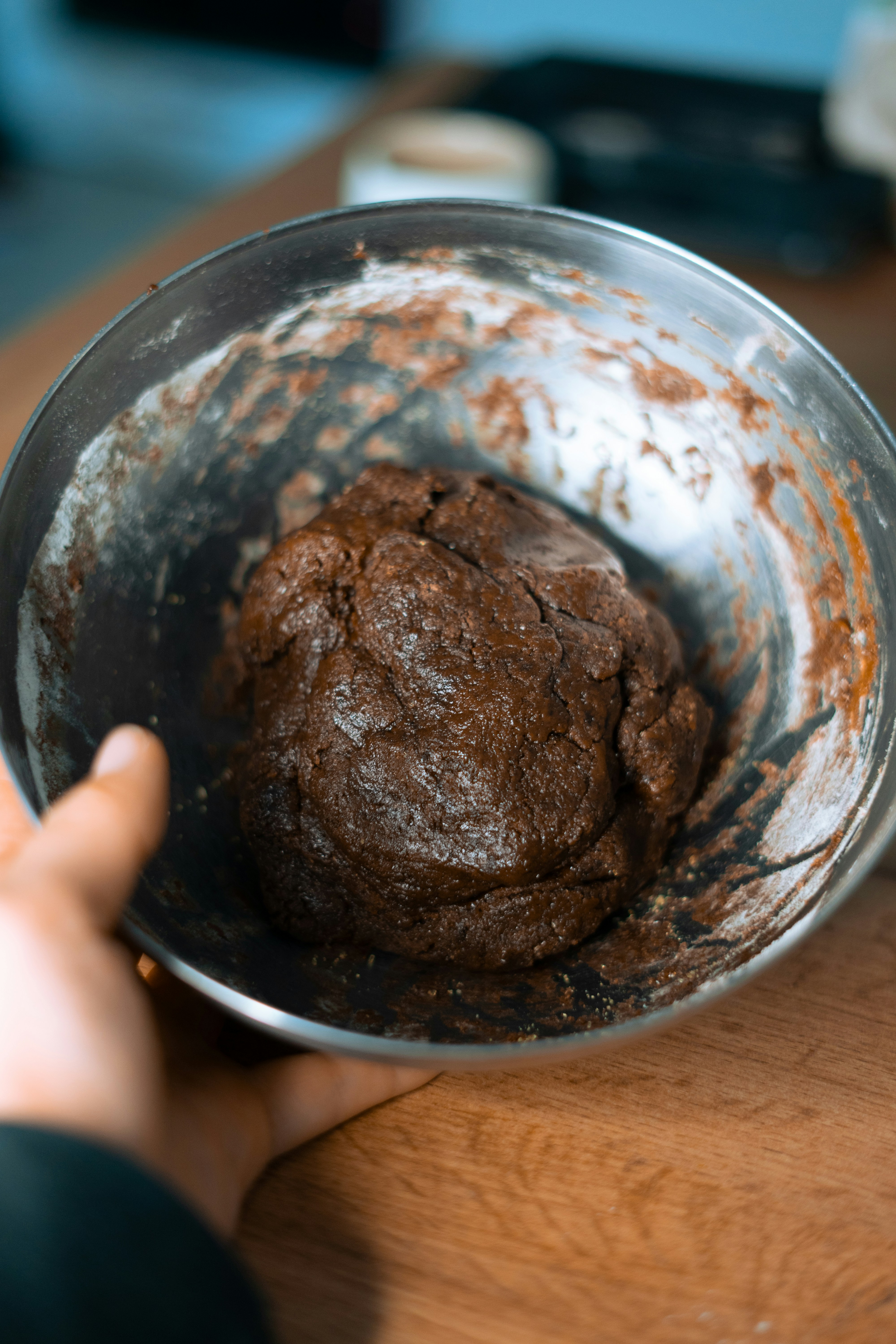 a person holding a metal bowl with a chocolate cookie in it