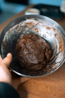 Brigadeiro balls being rolled by hand on a kitchen countertop