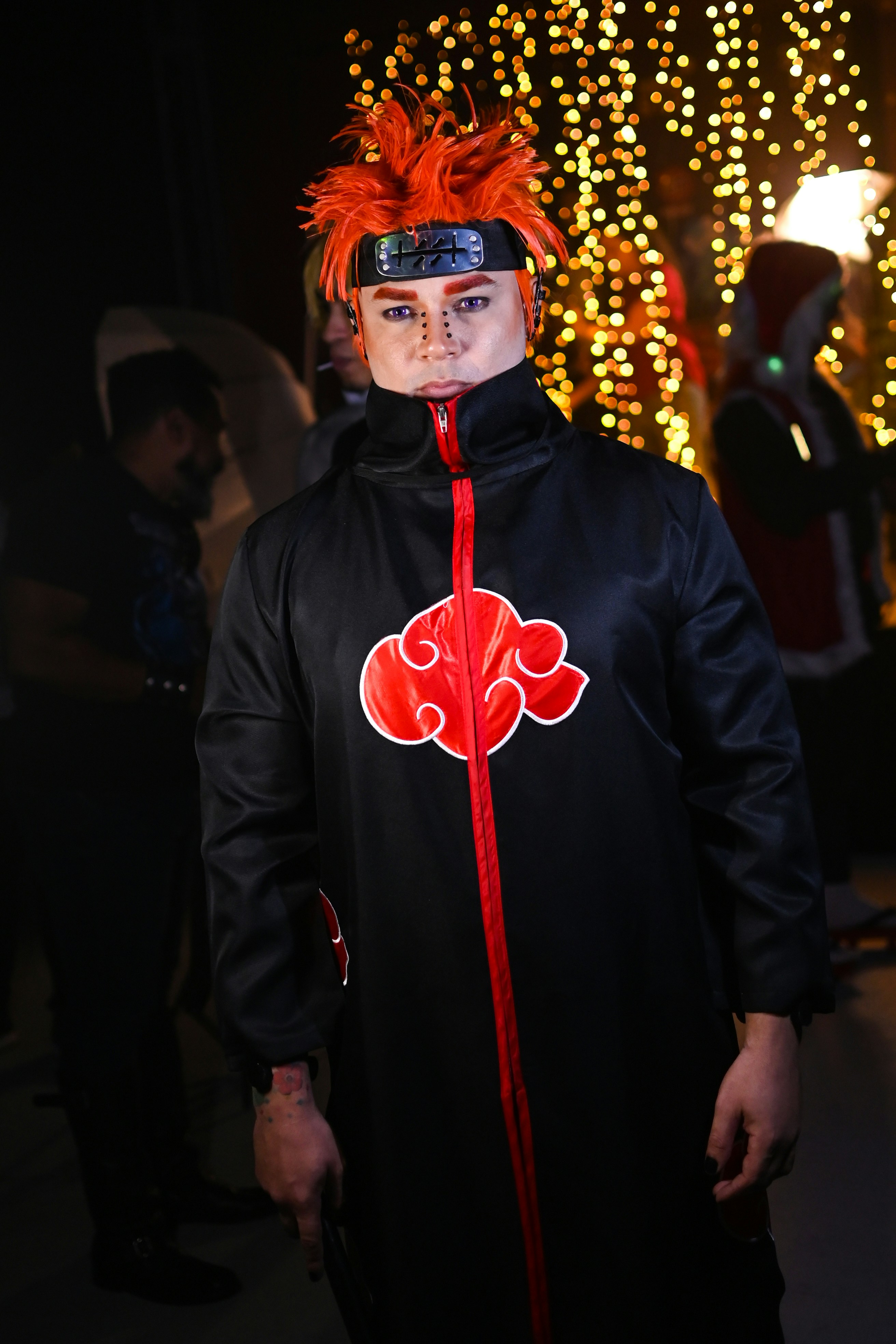 Seorang pria berjaket hitam dengan desain merah dan putih di wajahnya